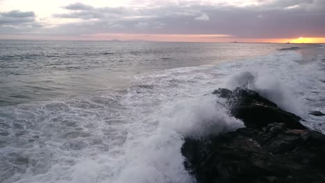 Flut,-Die-Bei-Sonnenuntergang-Hereinrollt-Und-Auf-Felsen-Stürzt