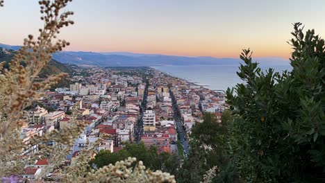 Timelapse-De-La-Puesta-De-Sol-Sobre-Una-Ciudad-Ocupada-En-La-Costa-De-Sicilia-Con-Montañas-Y-Mar