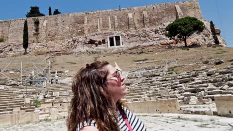 woman pointing at the acropolis from an ancient theatre, athens, greece