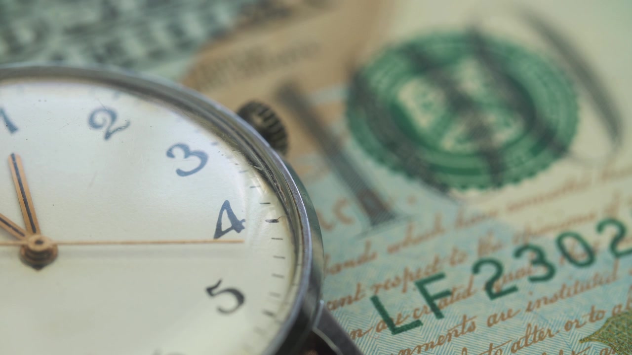 Primer plano de reloj vintage haciendo tictac sobre billetes de dólar estadounidense