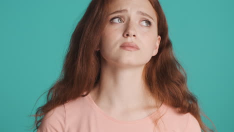 Redheaded-girl-in-front-of-camera-on-turquoise-background.