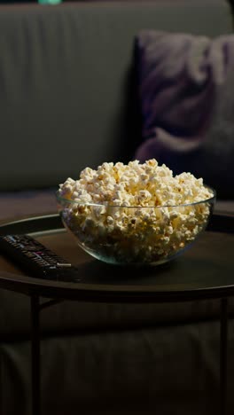 vertical video popcorn bowl on table in living room, close up panning shot