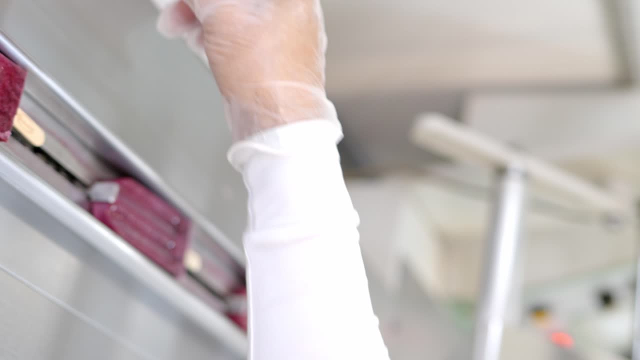 trabajador de la fábrica de helados poniendo paletas de uva y bayas en un cinturón de metal listo para ser envuelto para la futura venta de helados