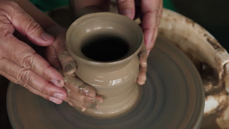persona que da forma a la arcilla en una rueda de cerámica