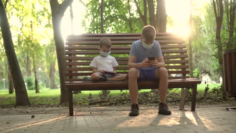 niños con máscaras médicas juegan con teléfonos inteligentes en el parque 01