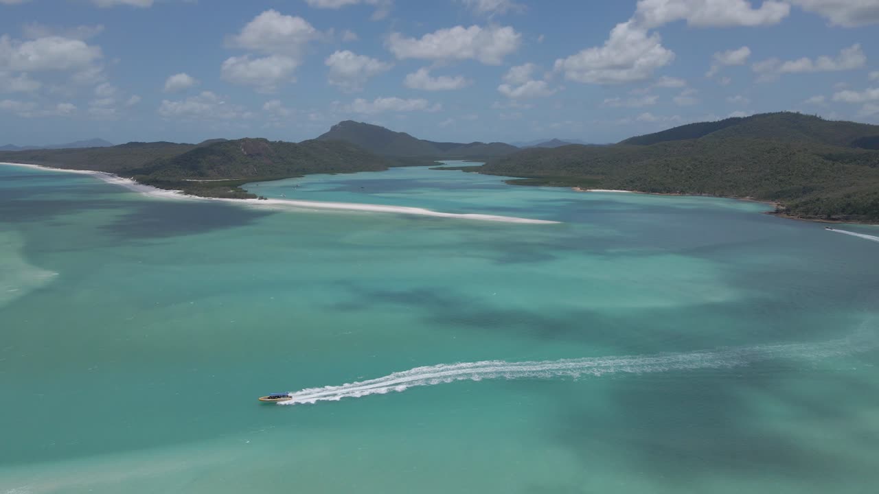 barco turístico navegando y dejando estela a través del mar de coral en la isla de whitsunday, australia