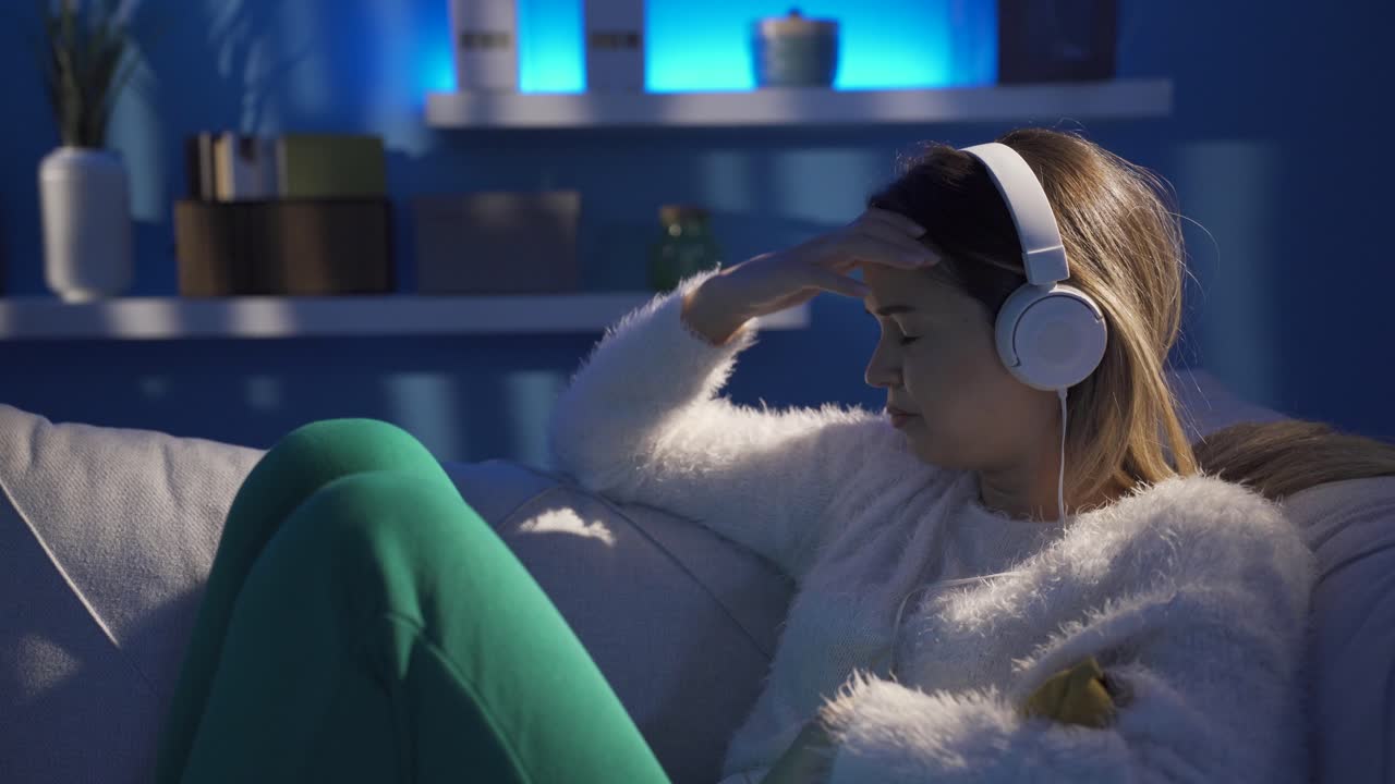 우울한 젊은 여성이 슬픈 음악을 듣고 있습니다.