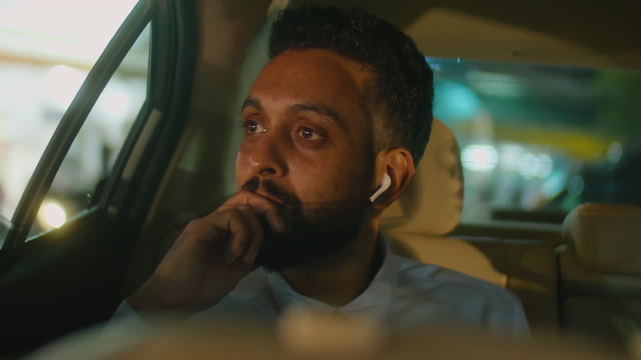 Businessman in Earphones Riding in Taxi at Night