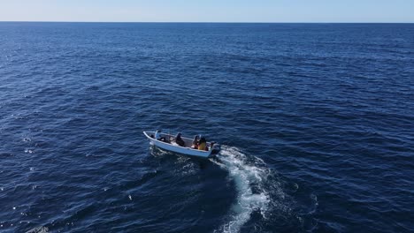 seguimiento aéreo de un pescador maniobrando un barco de fondo plano a través del océano abierto.
