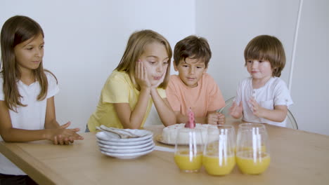 niña de cumpleaños emocionada haciendo un deseo y soplando una vela