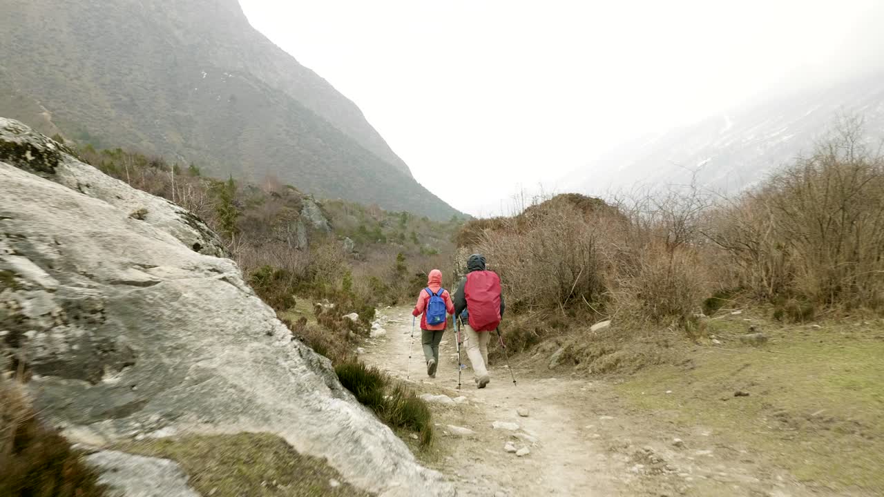 una pareja caminando por las montañas de nepal.