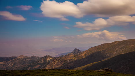 Shot-of-white-clouds-rapidly-moving-over-green-mountain-range-over-blue-sky-in-timelapse