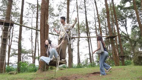 indonesian friends playing on a swing in forest during outdoor travel adventure