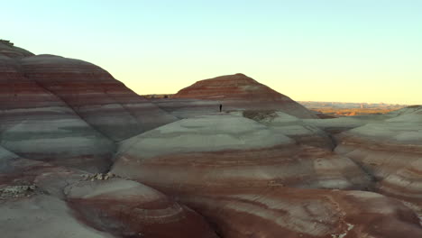 Drone-flying-over-man-in-colourful-rock-formations-at-Mars-desert-research-station-in-Utah,-United-States