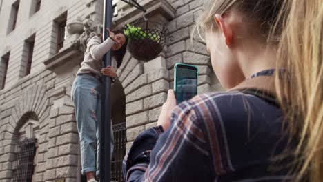 over the shoulder view of a caucasian filming her friend in the street