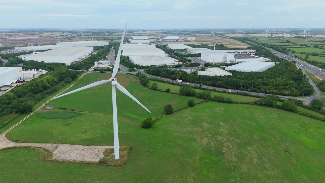 Drone aerial cinematic close up view of windmills for renewable energy alongside warehouses, factories and business hubs Lutterworth United Kingdom