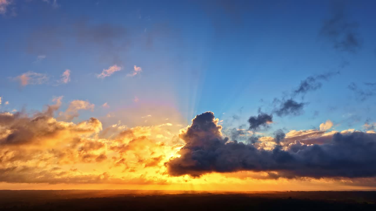 Golden hour over sun rays illuminate dark landscape with orange clouds silhouette, backdrop