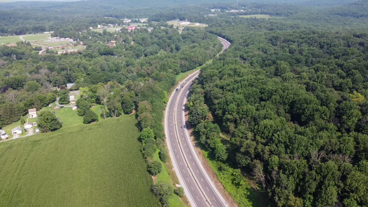 una vista aérea de los vehículos que circulan por una carretera dividida en el campo cubierto de árboles