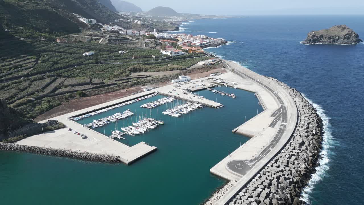Parallasse aerea intorno a Porto Garachico in una giornata di sole con campi a terrazze sovrastanti