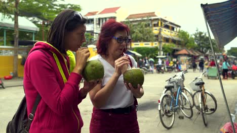 women drink milk from coconut on the street