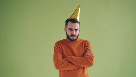 man wearing a party hat looking unhappy