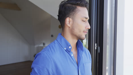 retrato de un hombre biracial feliz mirando a la cámara y sonriendo, en cámara lenta
