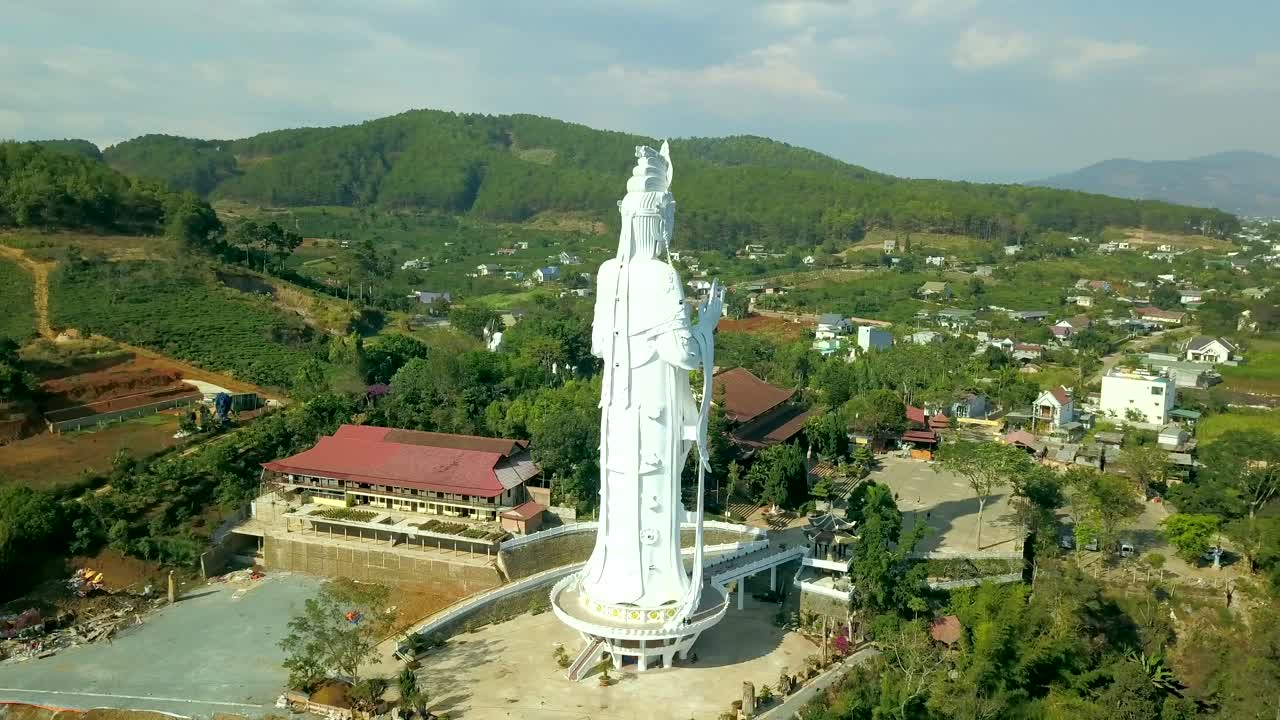 Drone footage of giant religious statue and Elephant waterfall on stones in Vietnam, Dalat. Village and road with pond and trees and nature.