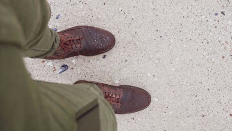 Man-Standing-On-A-Sandy-Beach-Looking-Down-With-Wet-Brown-Leather-Shoes---High-Angle-Shot