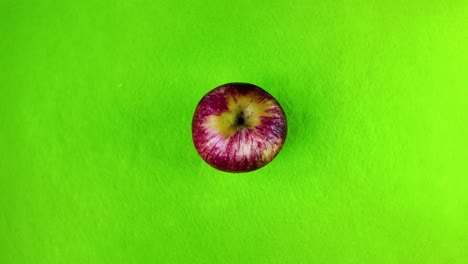 single red apple rotating on a bright green background