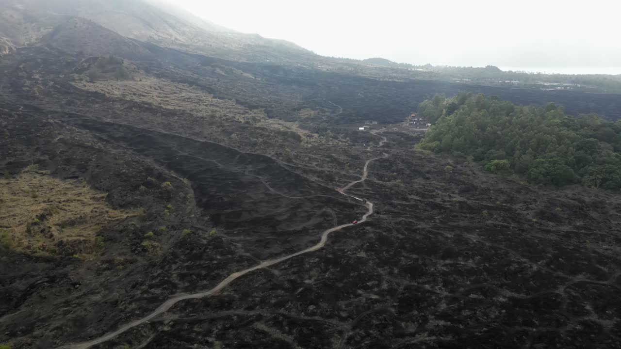 vehículo solitario conduce por un camino de tierra a través de un campo de lava volcánica en bali
