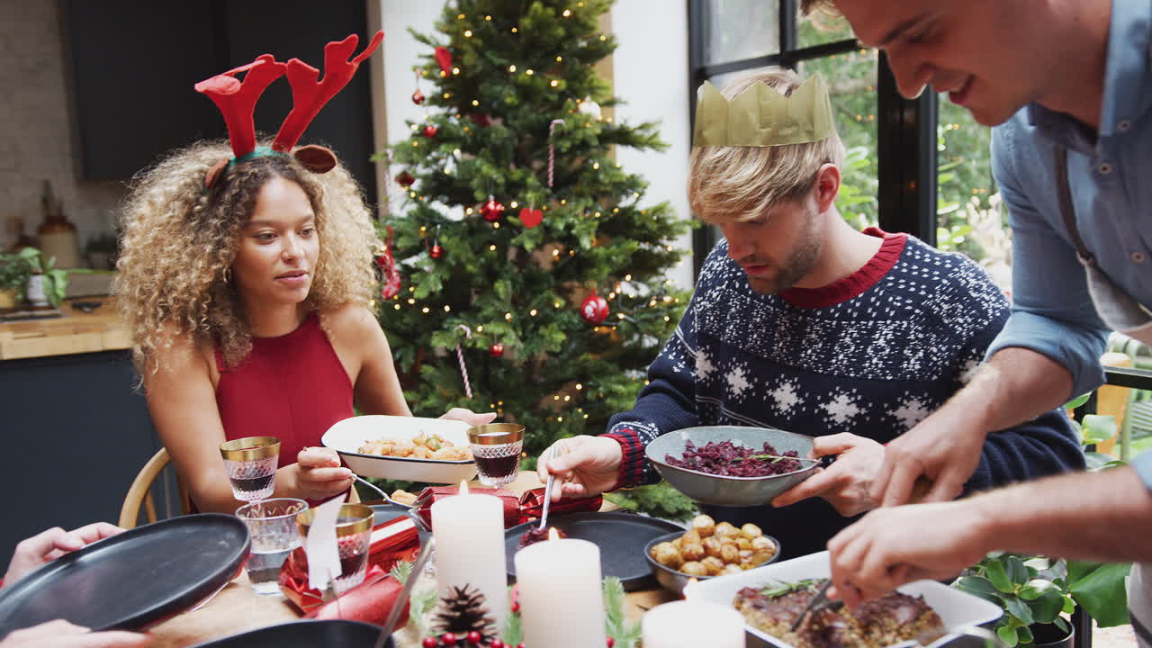 grupo de amigos sentados alrededor de la mesa de comedor en casa mientras se sirve la cena de navidad vegetariana