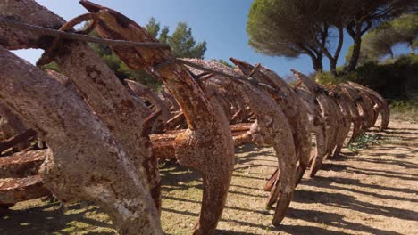 walking past row of rusty anchors covered in barnacles stored on land