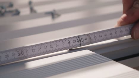 a craftsman measures a floorboard with a yardstick