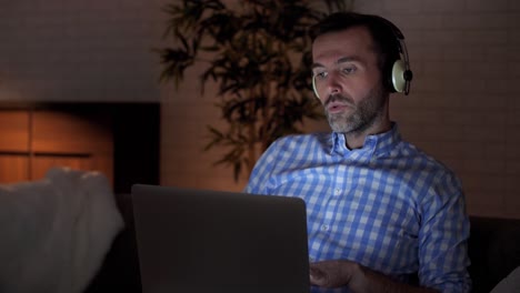 Man-using-laptop-and-listening-to-music-in-home-office