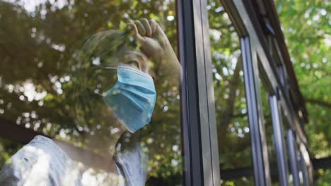 asian woman wearing face mask and looking through window