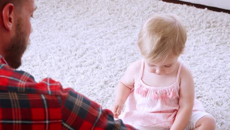 young dad playing xylophone with daughter in sitting room