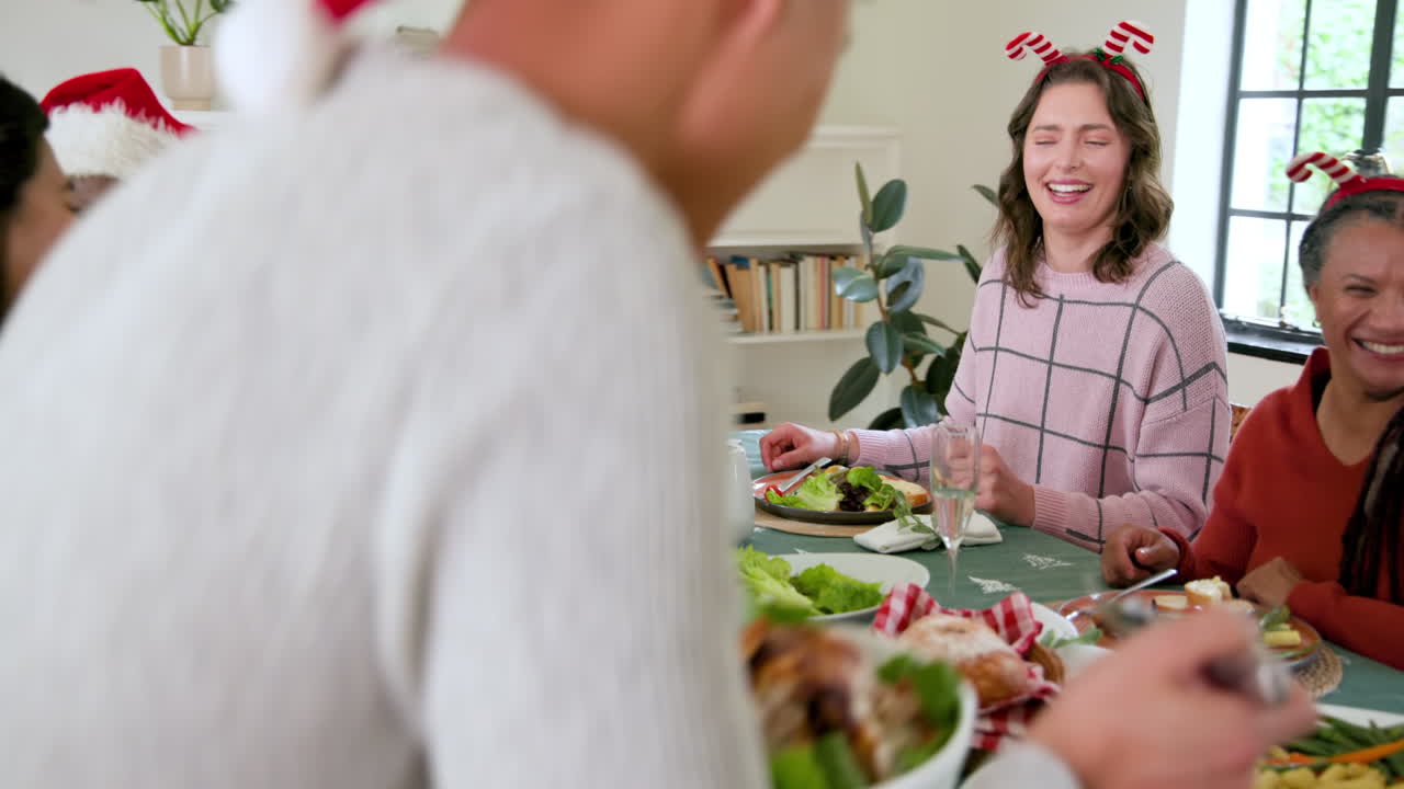 Diverse family enjoying festive Christmas meal together, laughing and sharing joyful moments
