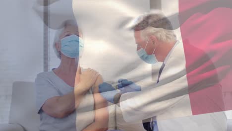 Animation-of-flag-of-frane-waving-over-doctor-wearing-face-mask-and-vaccinating-senior-woman
