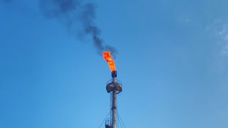 burning gas flare smoking black in bangladesh on a sunny day with some clouds