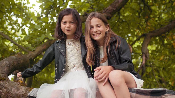Duas meninas felizes sentadas em uma árvore