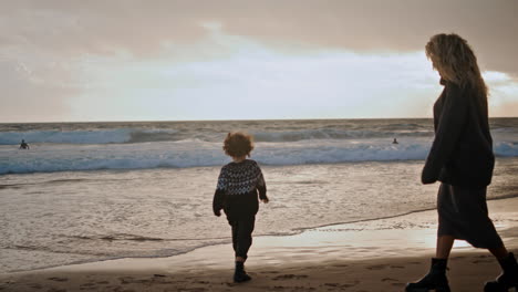 little boy playing shore on sunset. joyful son spending weekend with mother.