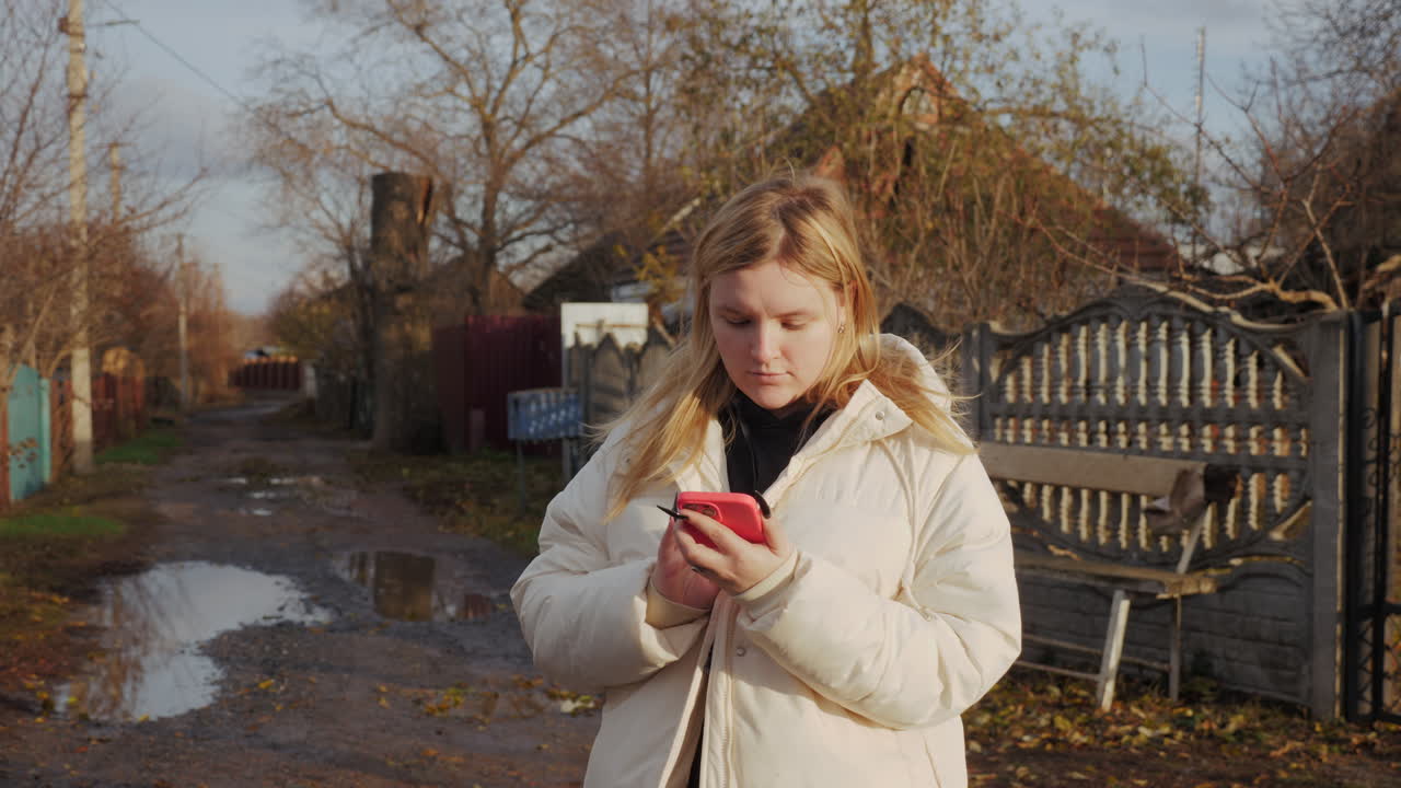 Kvinne bruker telefon i landlig høstmiljø