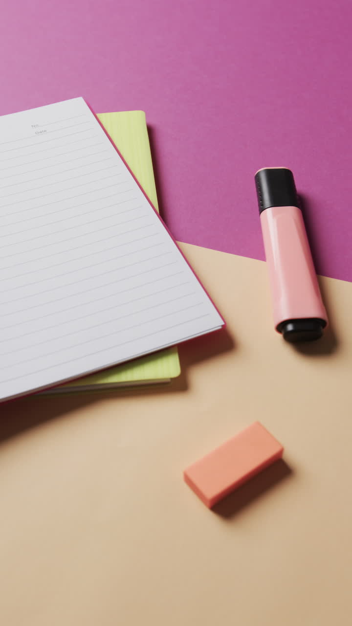 Vertical video of close up of school stationery on purple and beige background, in slow motion