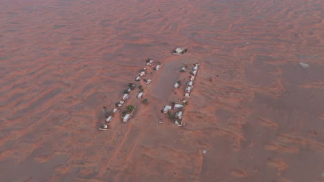 Aerial-view-of-an-empty-abandoned-village-and-homes-covered-in-desert-sand-near-Dubai