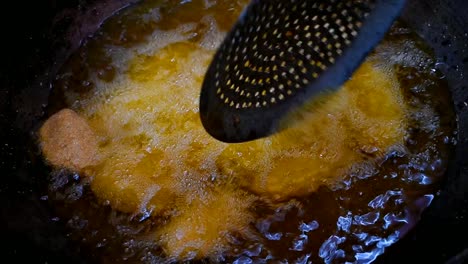 man stirring flour dough in a deep frying pan