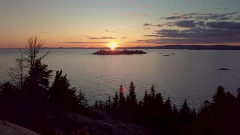 flying over smooth rock to blue lake at sunset, drone aerial wide dolly in