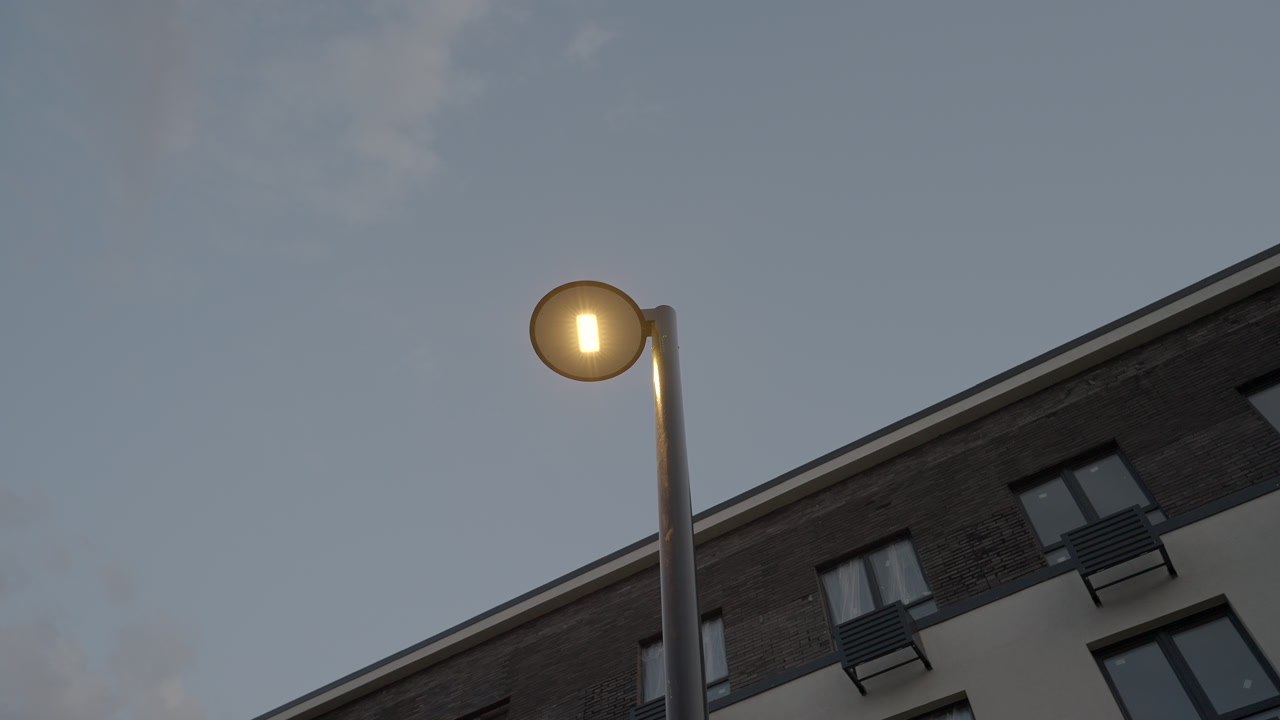 Twilight Sky With Glowing Streetlamp, Singleheaded Pole Rising Above Apartment Rooftop, Warm LED Core Visible