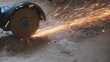 manos de trabajador cortando tubo de metal con sierra circular con chispas naranjas. concepto de construcción. metal cortado por sierra circular de mano de trabajador.