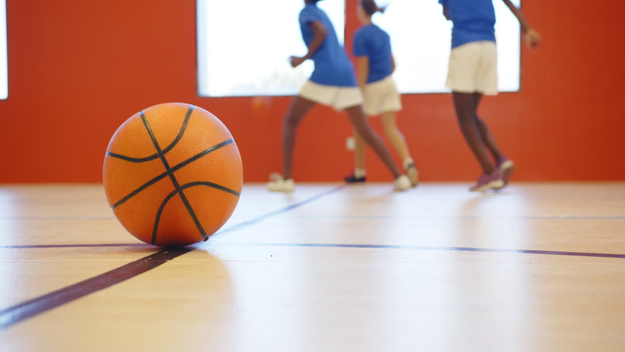 Playing basketball in school gym, kids practicing and having fun together