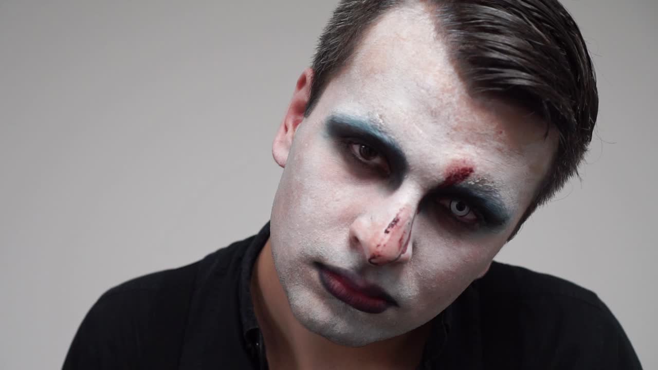 Man with face paint looking at camera and showing tongue, portrait closeup